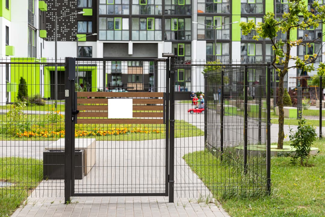 gate-with-blank-tablet-of-entrance-in-yard-min